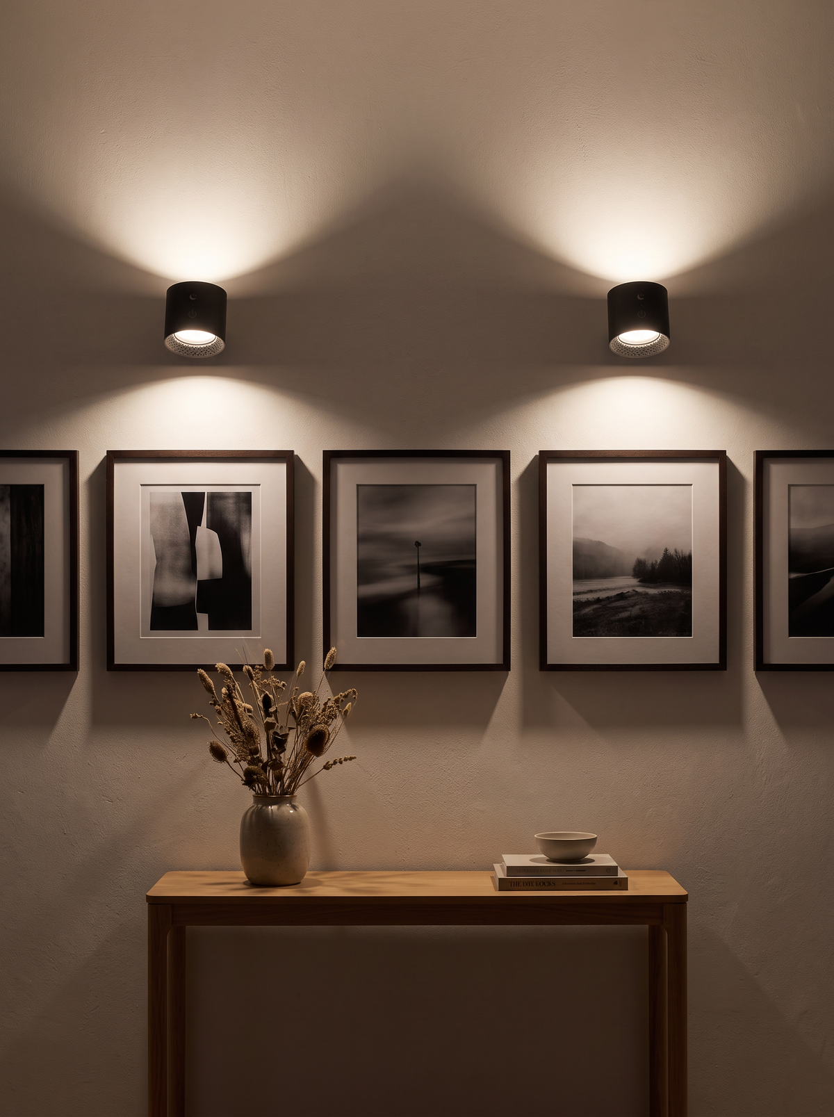 Two cordless wall lights washing light over a hallway gallery wall